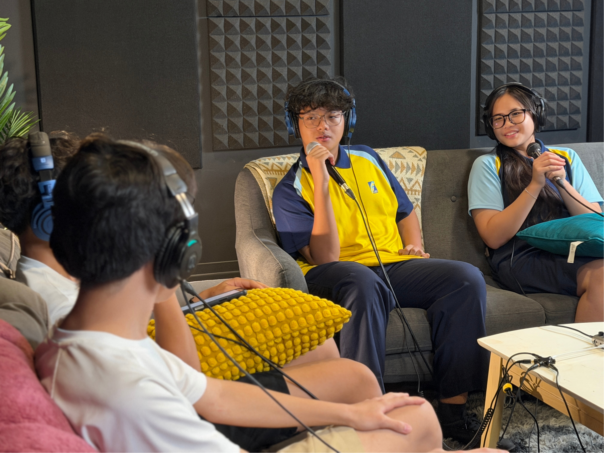 Students in a recording studio, wearing headsets and holding microphones in their hands